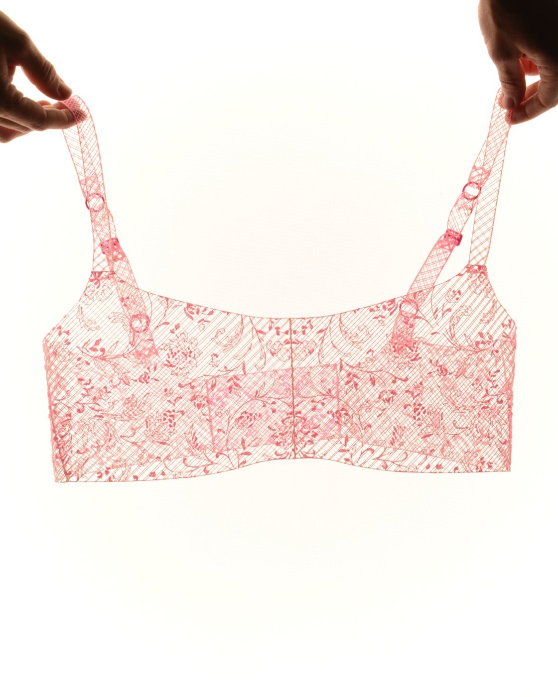 Pink 3D printed lace bra held up against the light